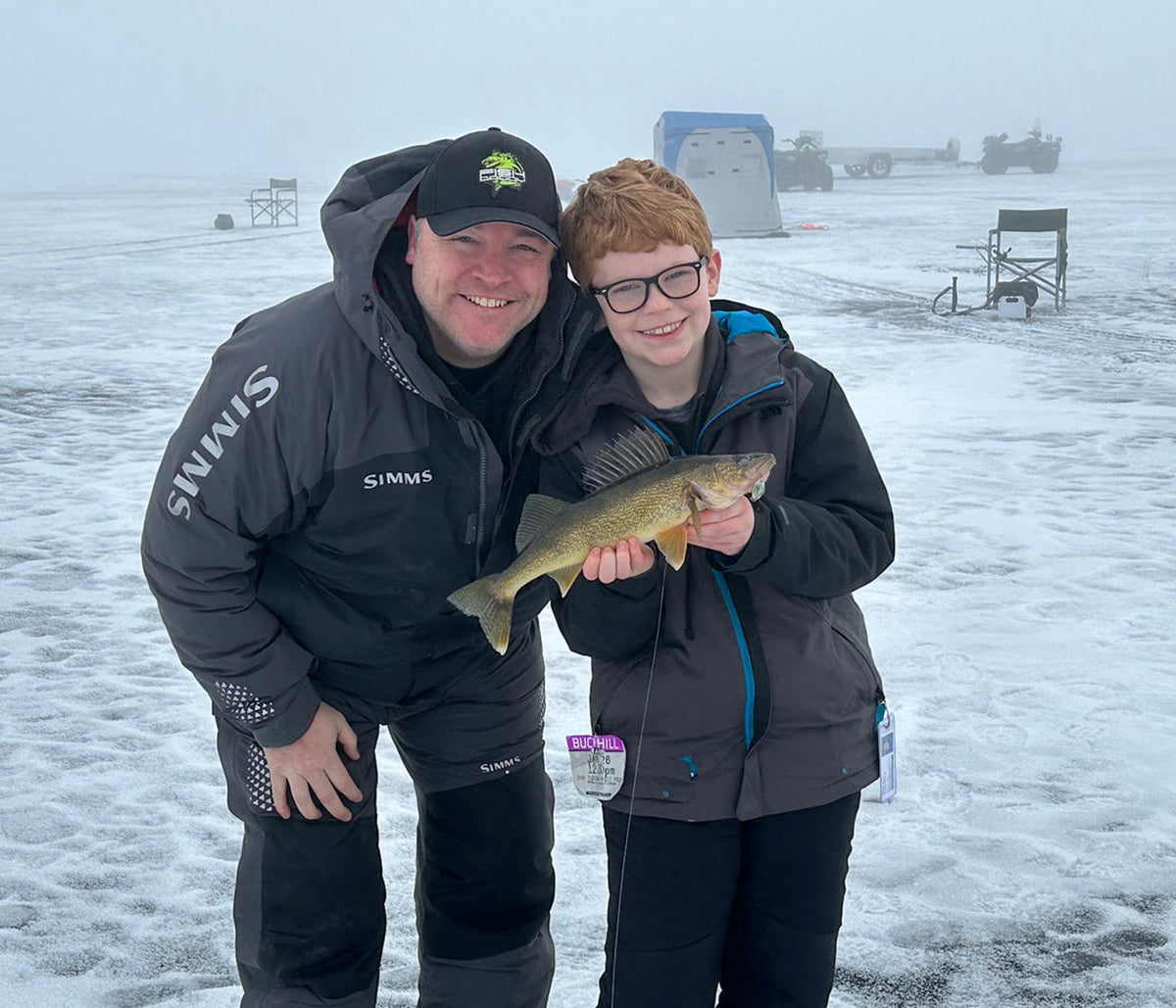 FishDaddy angler and young angler holding a walleye while ice fishing
